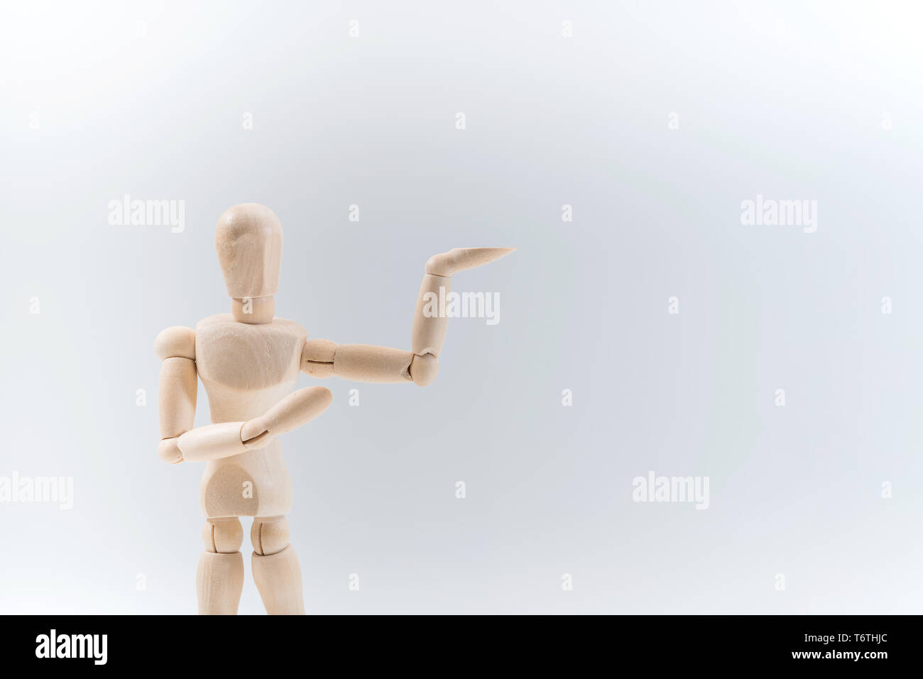 Wooden dummy proudly presents some invisible thing, isolated on white background, copy space for your object or text Stock Photo