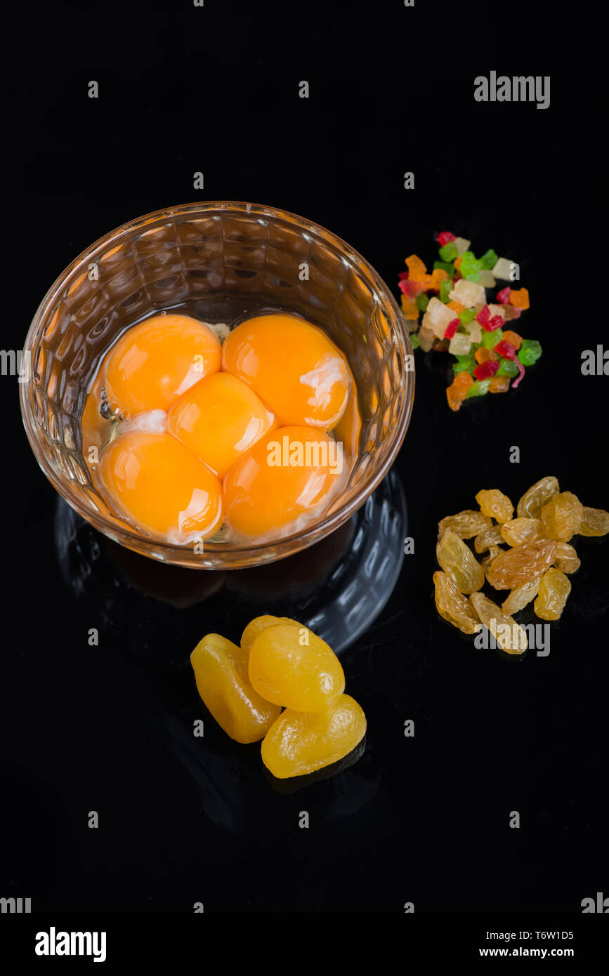 Bright yellow egg yolks in a glass bowl on black background