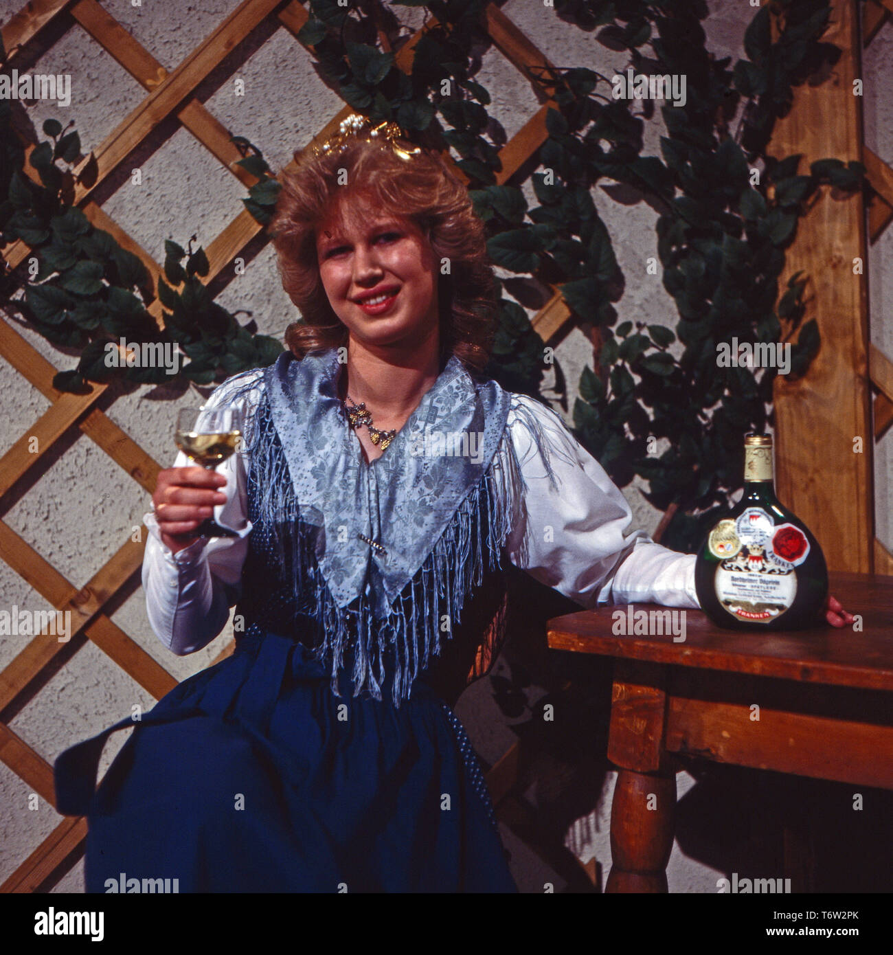 Weißblaue Musikparade, Volkstümliche Musiksendung, Deutschland 1985, Mitwirkende: Fränkische Weinkönigin 1985/1986 Monika Kram mit einer Flasche Frankenwein im Bocksbeutel Stock Photo