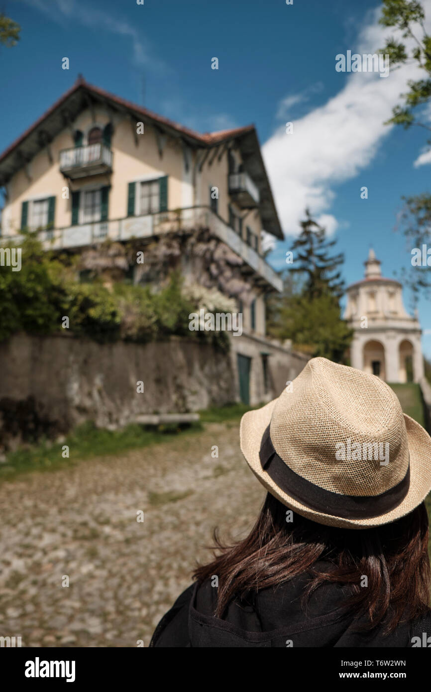 Traveler girl with Vintage Straw hat looking monumets and one of the XIVchapel along the path of the historic pilgrimage route from Sacred Mount or Sa Stock Photo