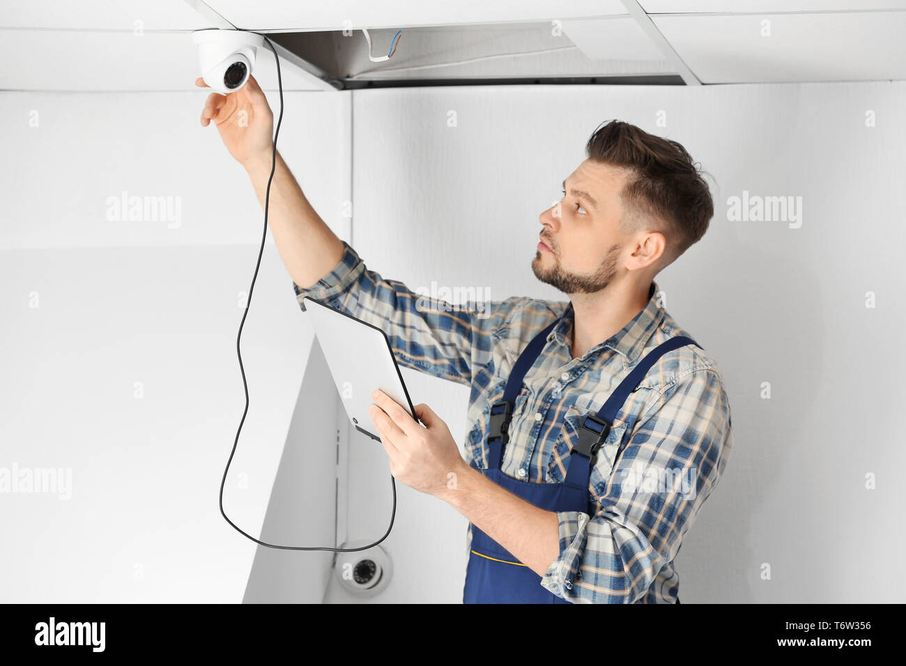 Electrician inspecting surveillance camera Stock Photo