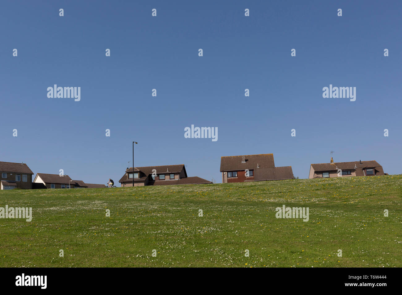 A local cyclist pedals uphill towards the houses of a