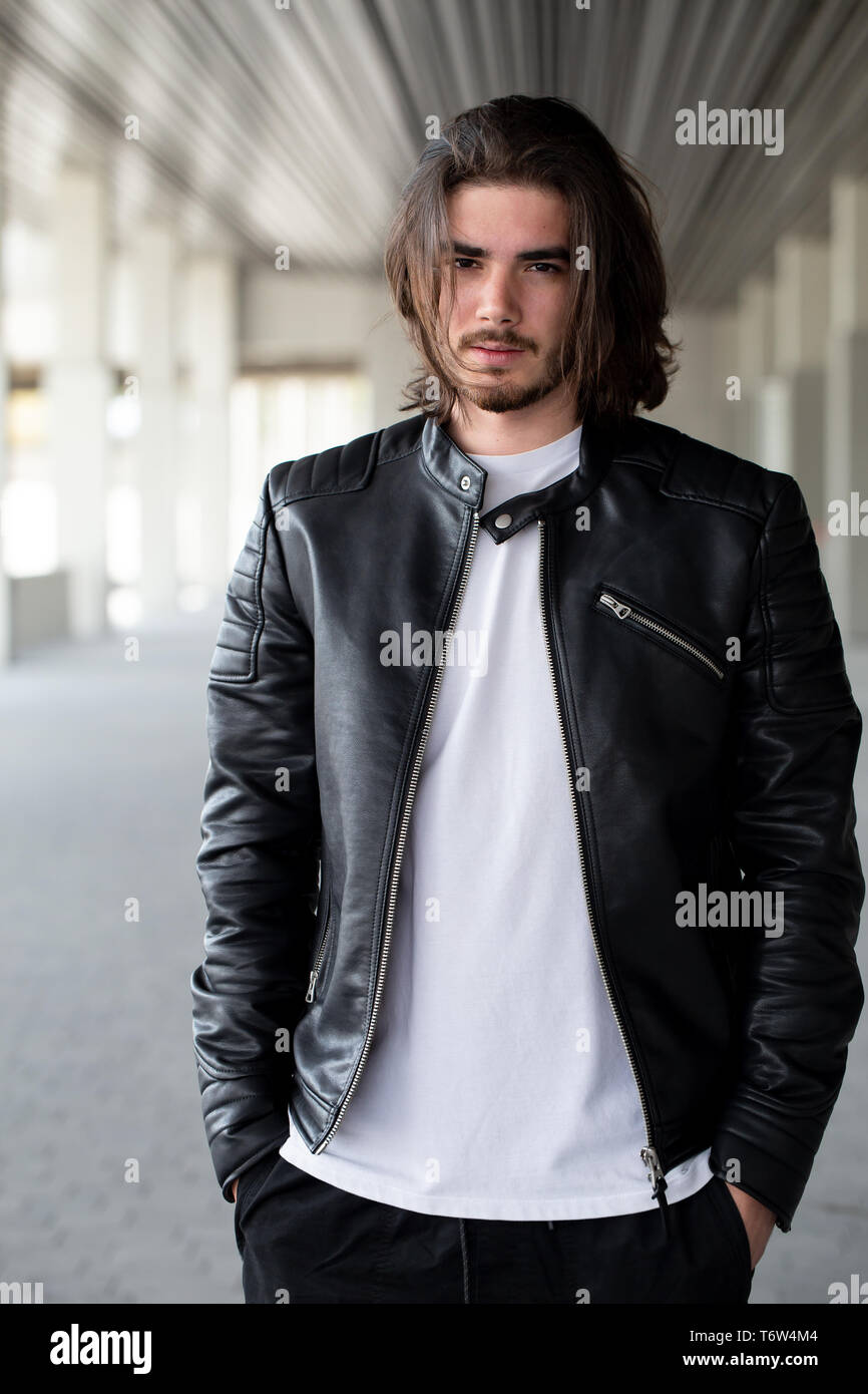 Half length portrait of handsome bearded man dressed in fashionable clothes standing on street against while wall background with area for advertising content. Handsome hipster guy posing on copy space Stock Photo
