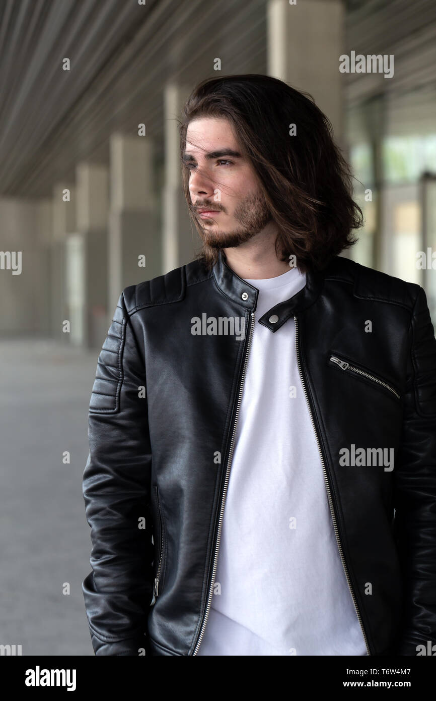 Half length portrait of handsome bearded man dressed in fashionable clothes standing on street against while wall background with area for advertising content. Handsome hipster guy posing on copy space Stock Photo