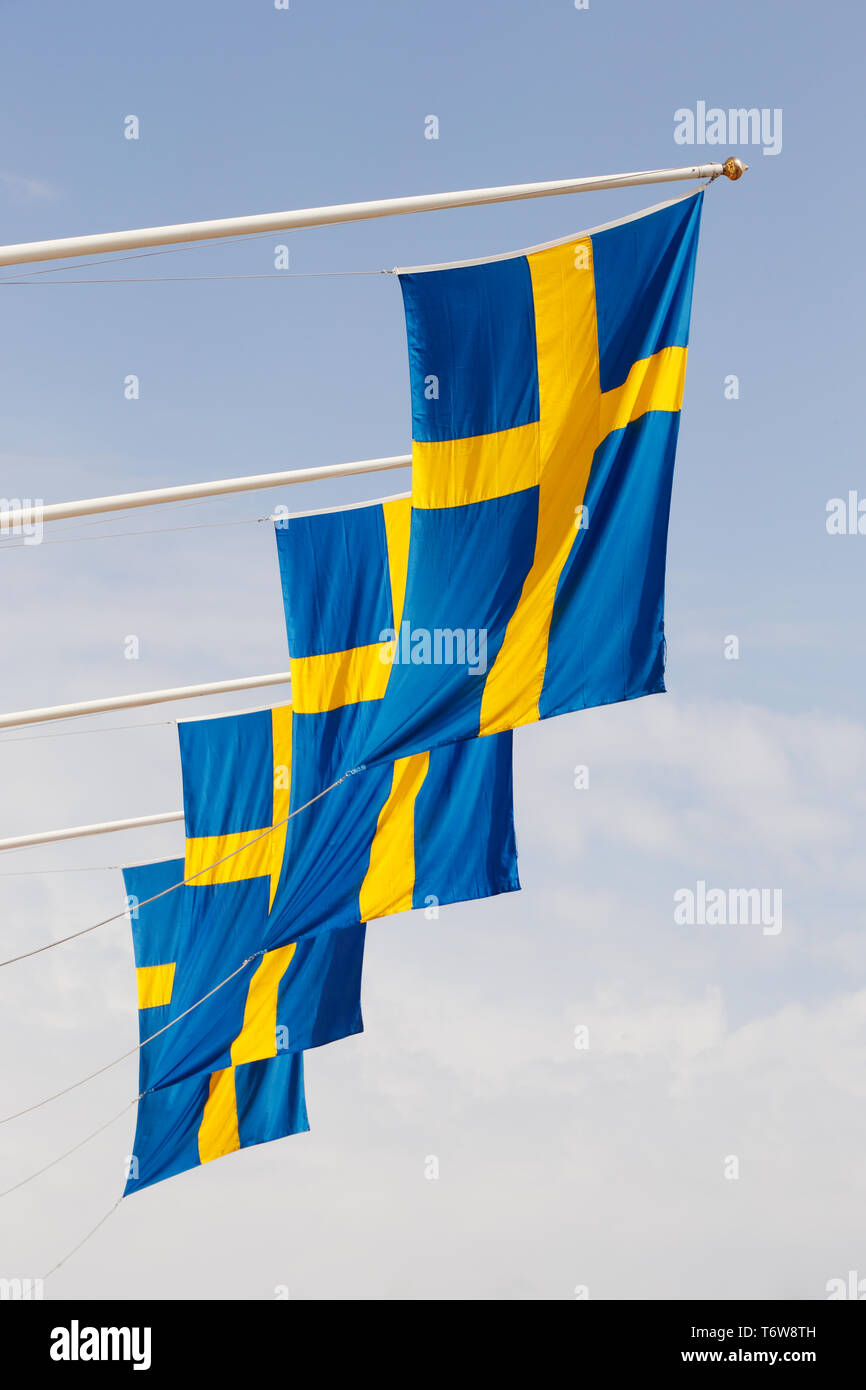 A group of Swedish flags haning from horisontal poles. Stock Photo