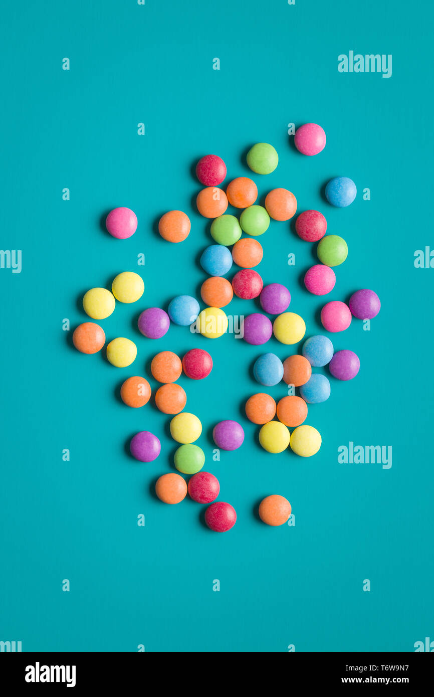 Colorful chocolate candy pills on blue background. Stock Photo