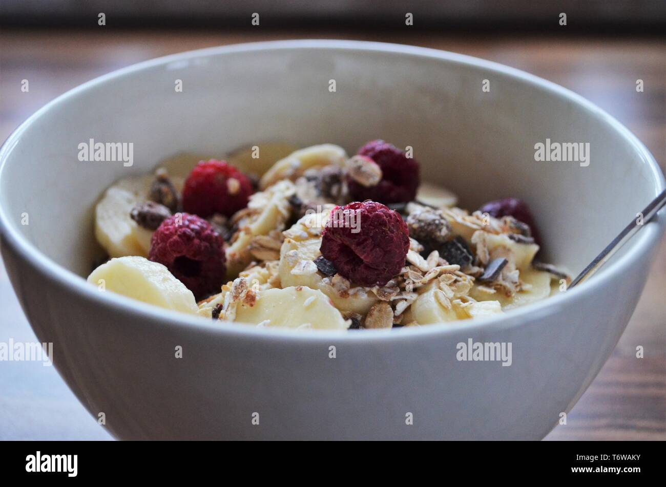 good morning breakfast, cereals in a bowl with bananas and raspberries