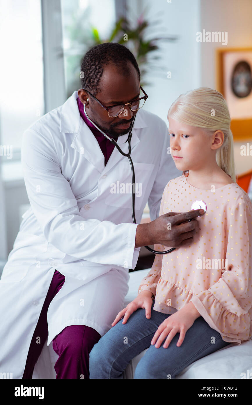 Doctor Using Stethoscope While Listening To Lungs Of Girl Stock Photo doctor-using-stethoscope-while-listening-to-lungs-of-girl-stock-photo