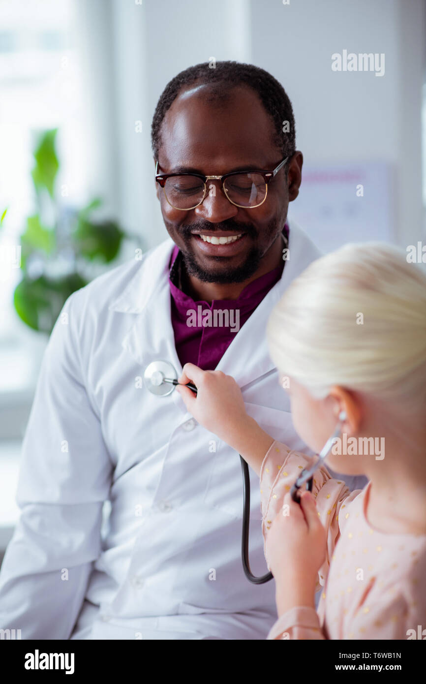 Dark-skinned pediatrician feeling happy spending day with daughter Stock Photo