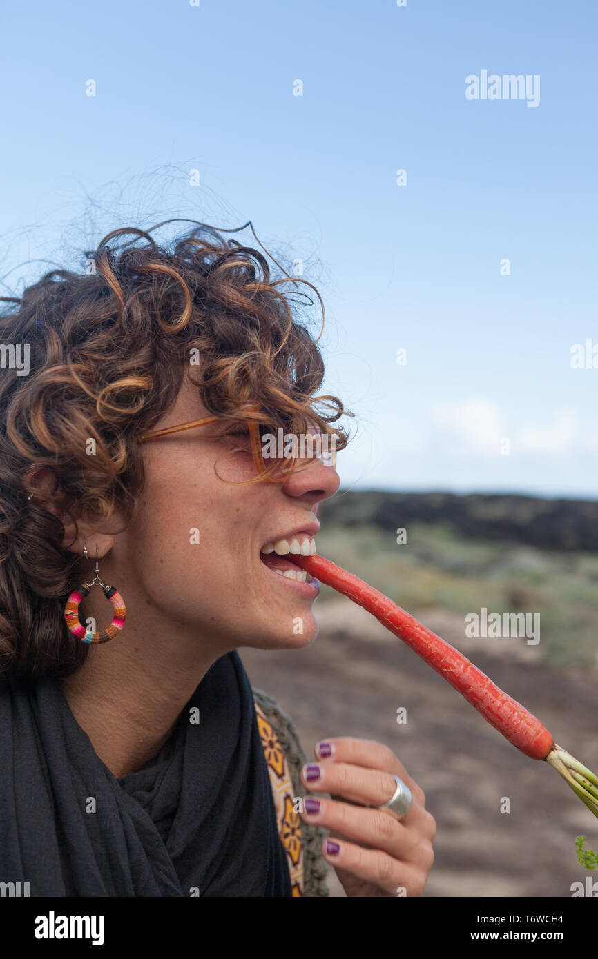 beautiful 20 30 yrs old girl smiling with a red carrot in her mouth Stock Photo