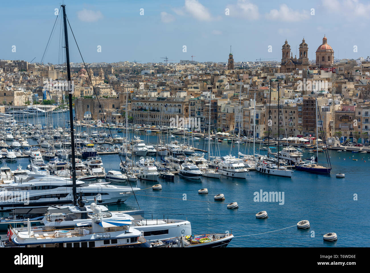 Luxury yachts and pleasure craft moored in Dockyard Creek of Valletta's Grand Harbour overlook by the Basilica of the Nativity of Mary, Senglea Stock Photo
