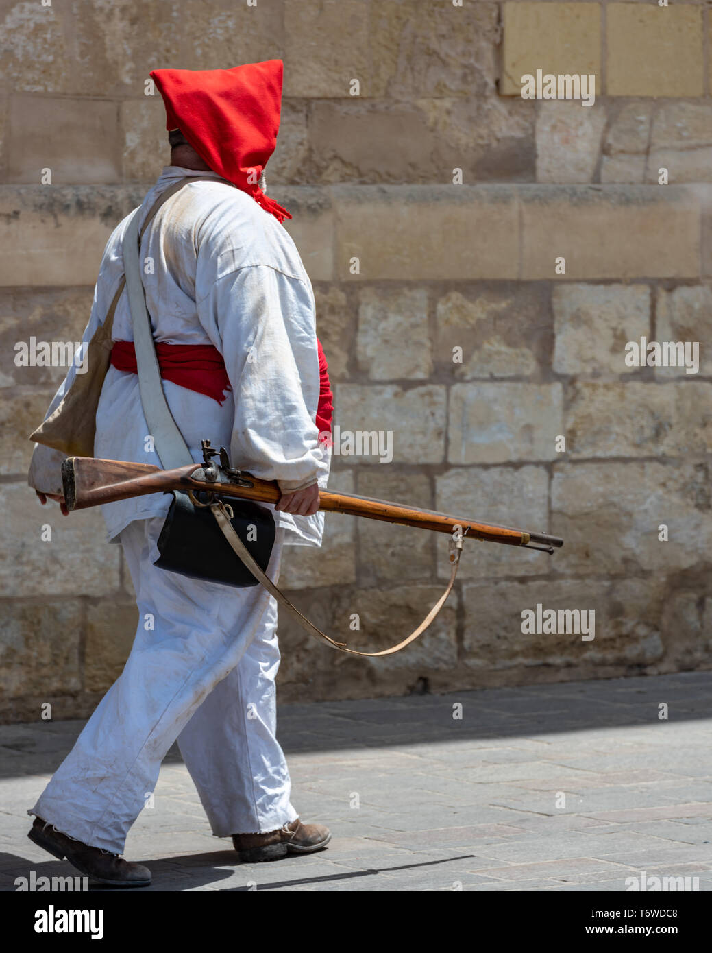 A historic re-enactment enthusiast in Napoleonic uniform marches past the Grandmaster Palace in  St George's Square, Valletta Stock Photo