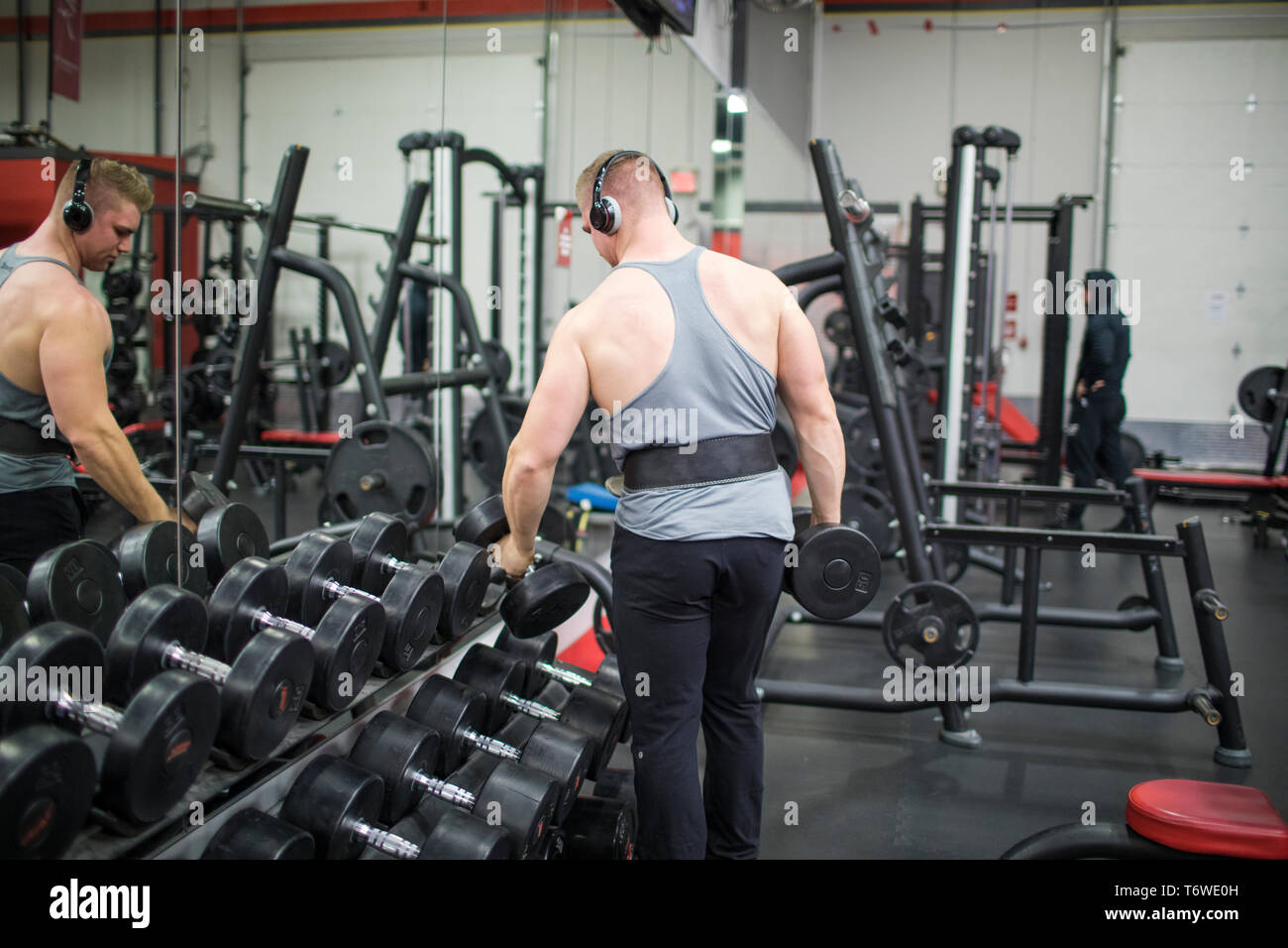 Bodybuilder selecting dumbbells of the rack at gym. Stock Photo