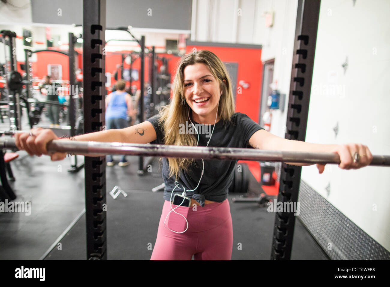 Smiling woman leaning on barbell at the gym Stock Photo