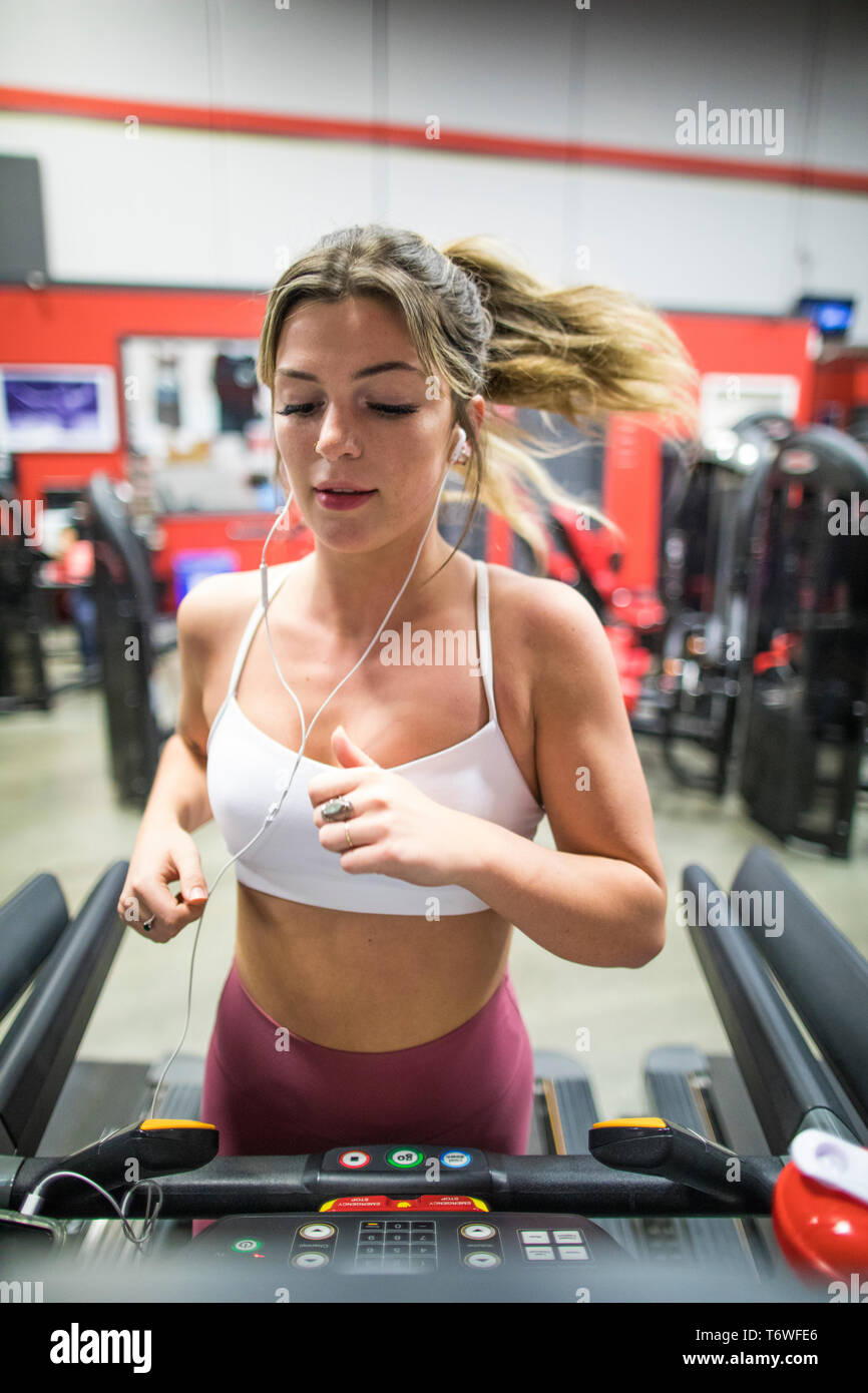 Attractive young woman running on treadmill at the gym. Stock Photo