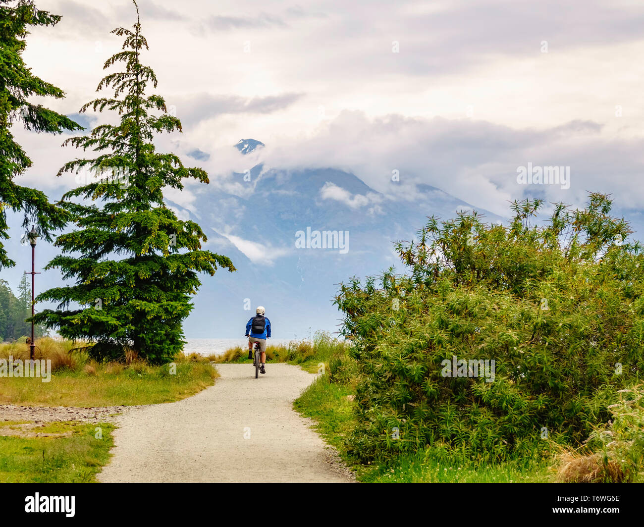 Bicyclist follows scenic trail by lake in Queenstown, New Zealand Stock Photo