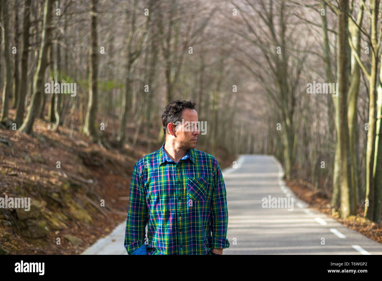 Front view of a man looking away,  standing on rural road in autumn Stock Photo