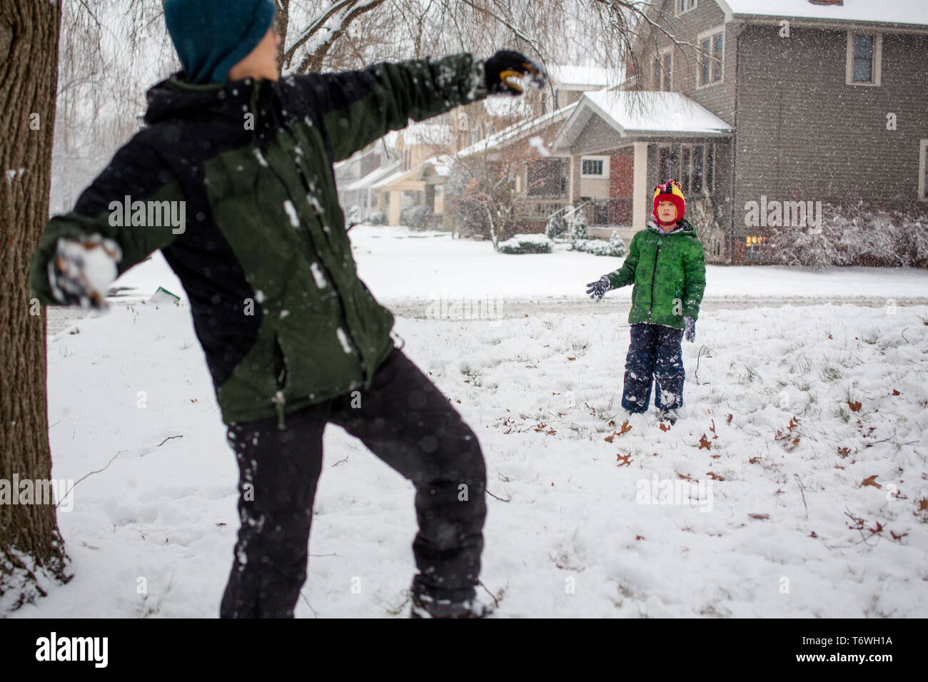 A father winds up to throw snowball at child Stock Photo