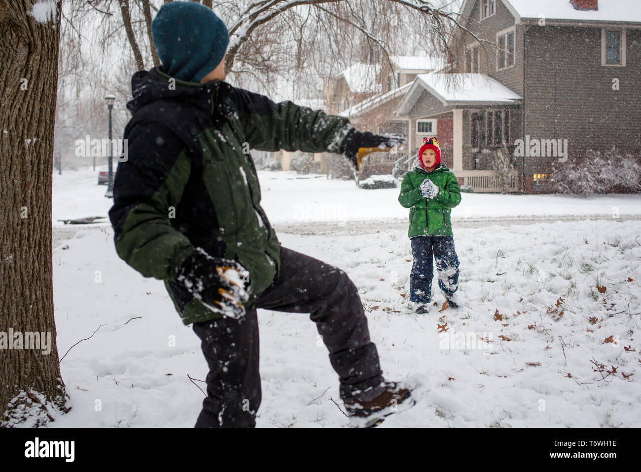 A father winds up to throw a snowball at son Stock Photo