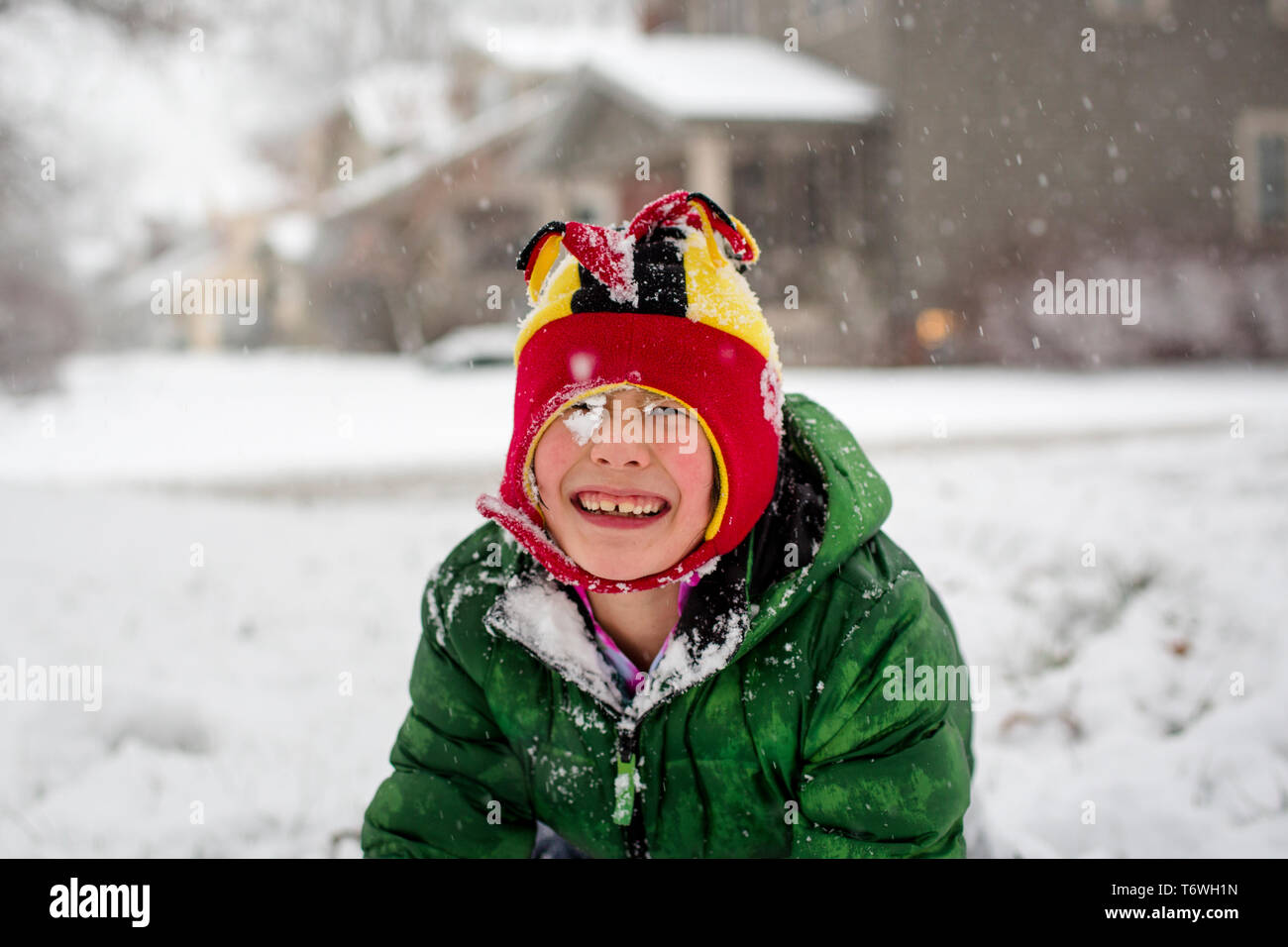 a joyful snow-covered child in a fuzzy hat plays in a snowstorm Stock Photo