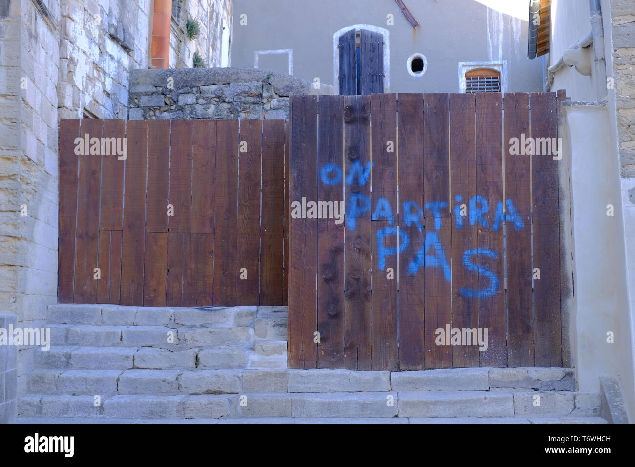 "on partira pas" writing (we will not leave) on fence of construction zone  in St-Gilles,  France Stock Photo
