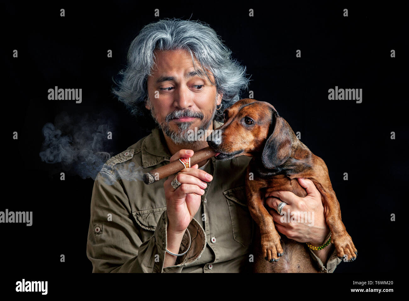 Funny portrait of middle aged man with sausage dog smoking cigars Stock Photo