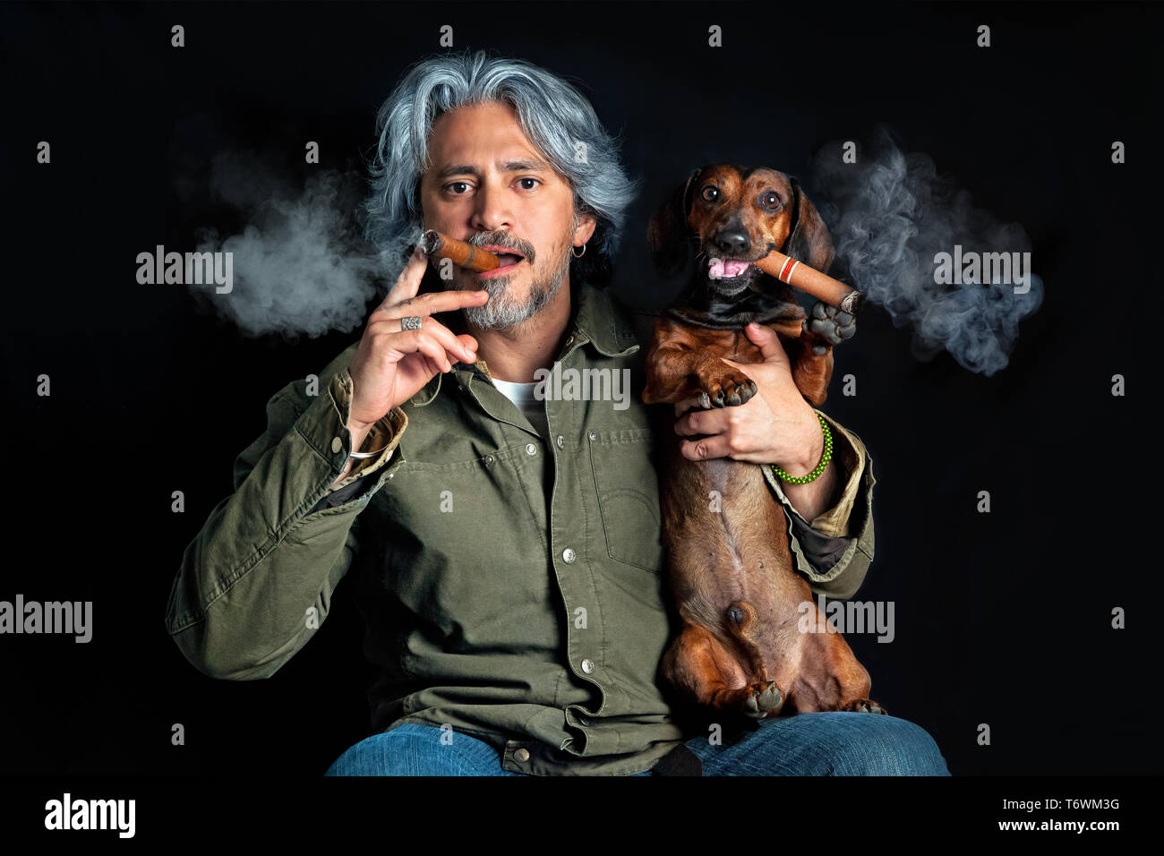Funny portrait of middle aged man with sausage dog smoking cigars Stock Photo
