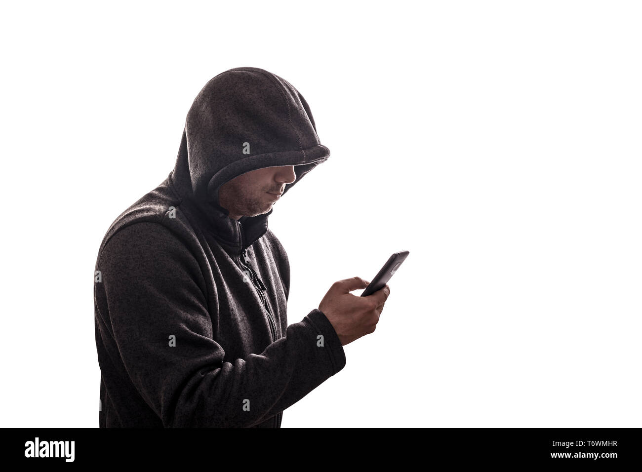 Hooded hacker holding smartphone isolated on white background Stock Photo