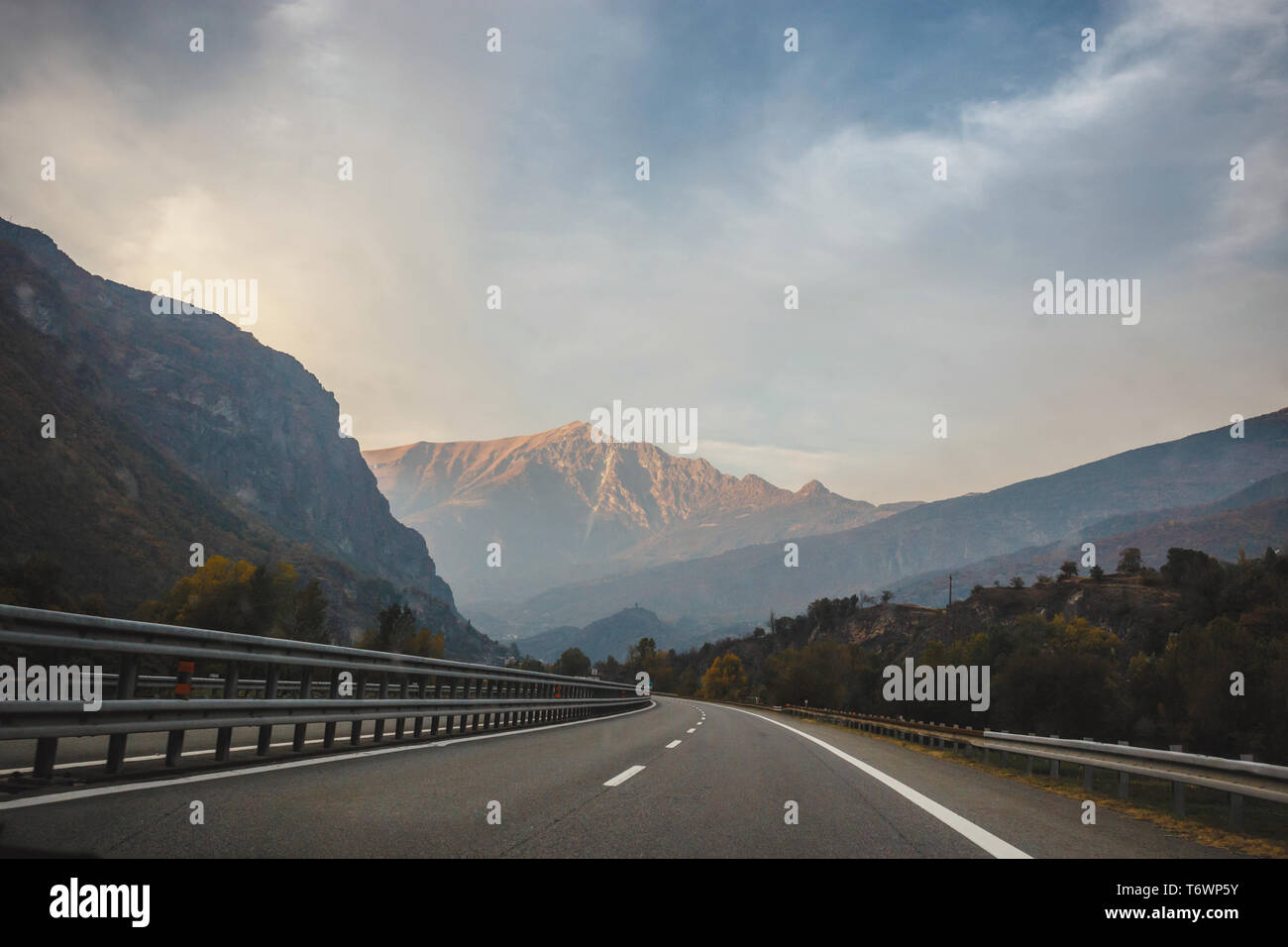 a mountain seen in the distance around a curve in the road Stock Photo