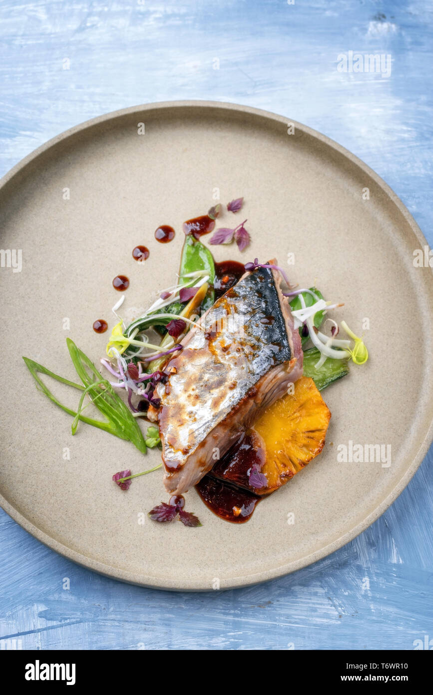 Modern style Japanese bonito tuna fish filet with vegetable and pineapple glazed in teriyaki sauce as top view on a plate with c Stock Photo