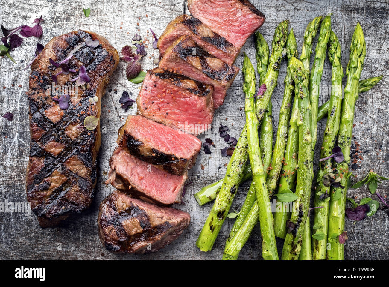 Traditional barbecue dry aged sliced roast beef steak with green asparagus  as top view on an old backing form Stock Photo - Alamy