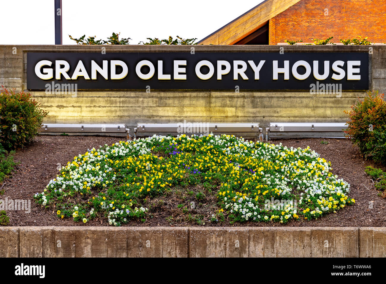 A sign at the Grand Ole Opry surrounded by flower beds with the venue behind it. Stock Photo