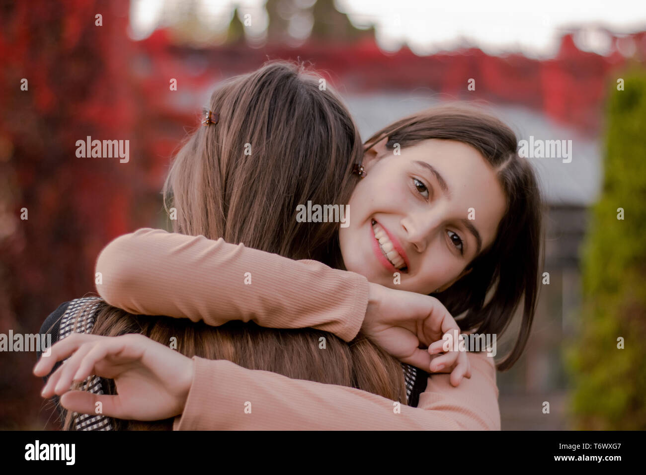 Smiling cute girl hugs his girlfriend tightly Stock Photo