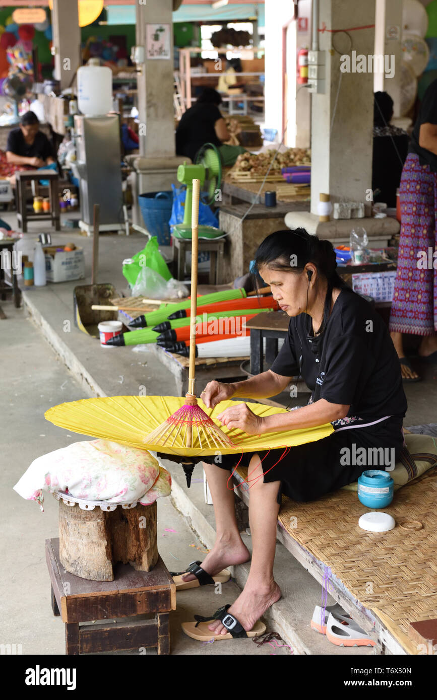 Thai woman worker attaching the wooden stretchers to a paper umbrella at the Umbrella Making Centre, Bo Sang, Chiang Mai Province, Thailand Stock Photo