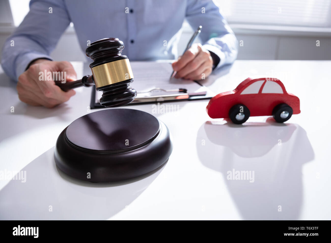 Wooden Toy Car In Front Of Judge Gavel On The Table Background Stock Photo