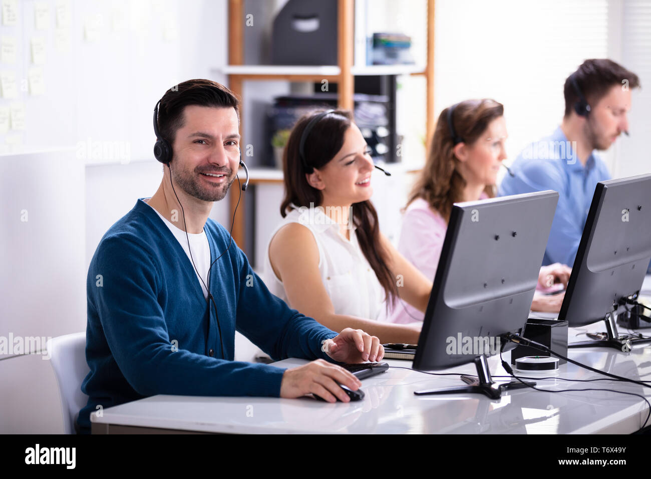 Happy Young Customer Service Executives Using Earphones Working In Call