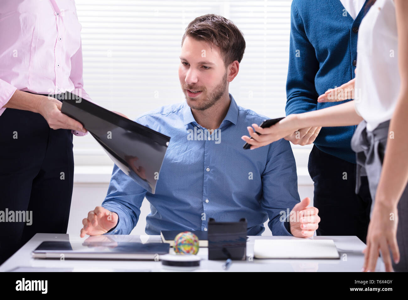 Young Businessman Looking At Document Shown By Partner Stock Photo