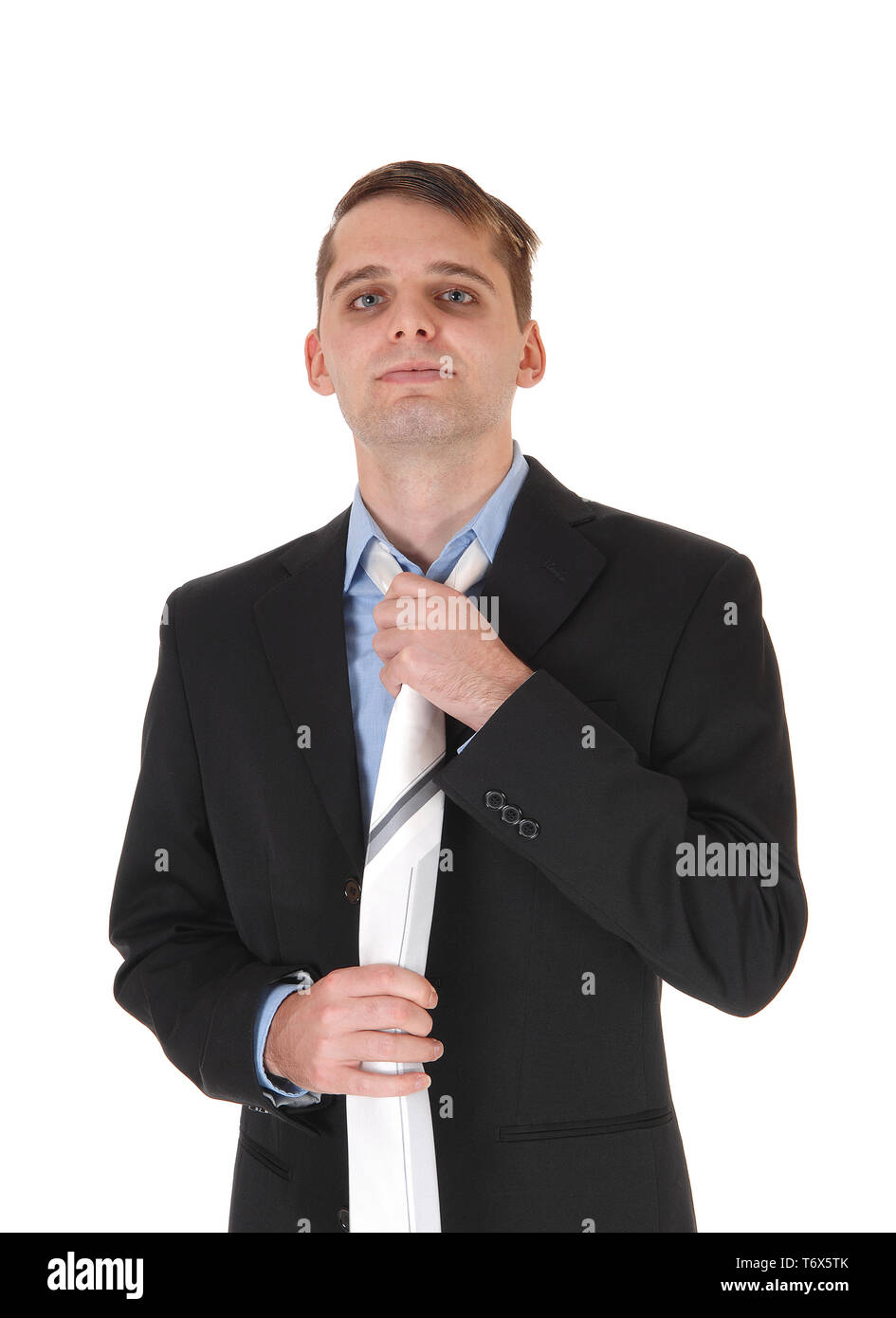 Young man standing in a suit fixing tie Stock Photo Alamy