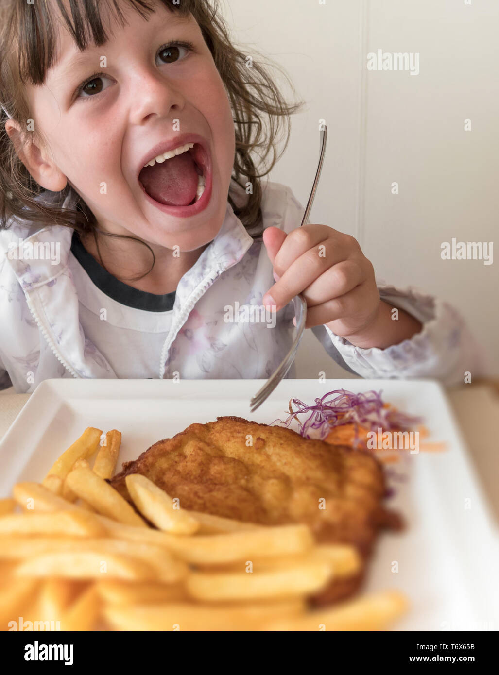 Little Italian girl eating breaded meat and french fries Stock Photo