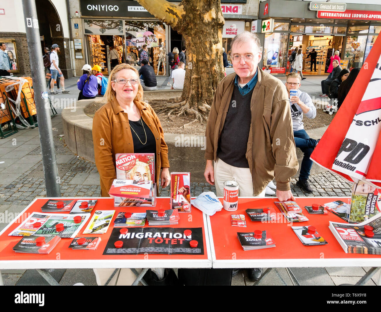 Munich, Bavaria, Germany. 2nd May, 2019. Renate Werlberger and Karl Richter of the neonazi NPD and BIA respectively while holding an information session for the NPD with ''migration kills'' on the table. The neonazi NPD party organized an information table in one of the most-traveled districts of Munich- the pedestrian zone in the city center where shoppers, tourists and workers cross. Behind the table was Munich city councilman Karl Richter, part of the neonazi group Buergerinitiativ Auslaender Stopp (Citizen Initiative to Stopp Foreigners) and Renate Werlberger of the NPD. Both parties ar Stock Photo