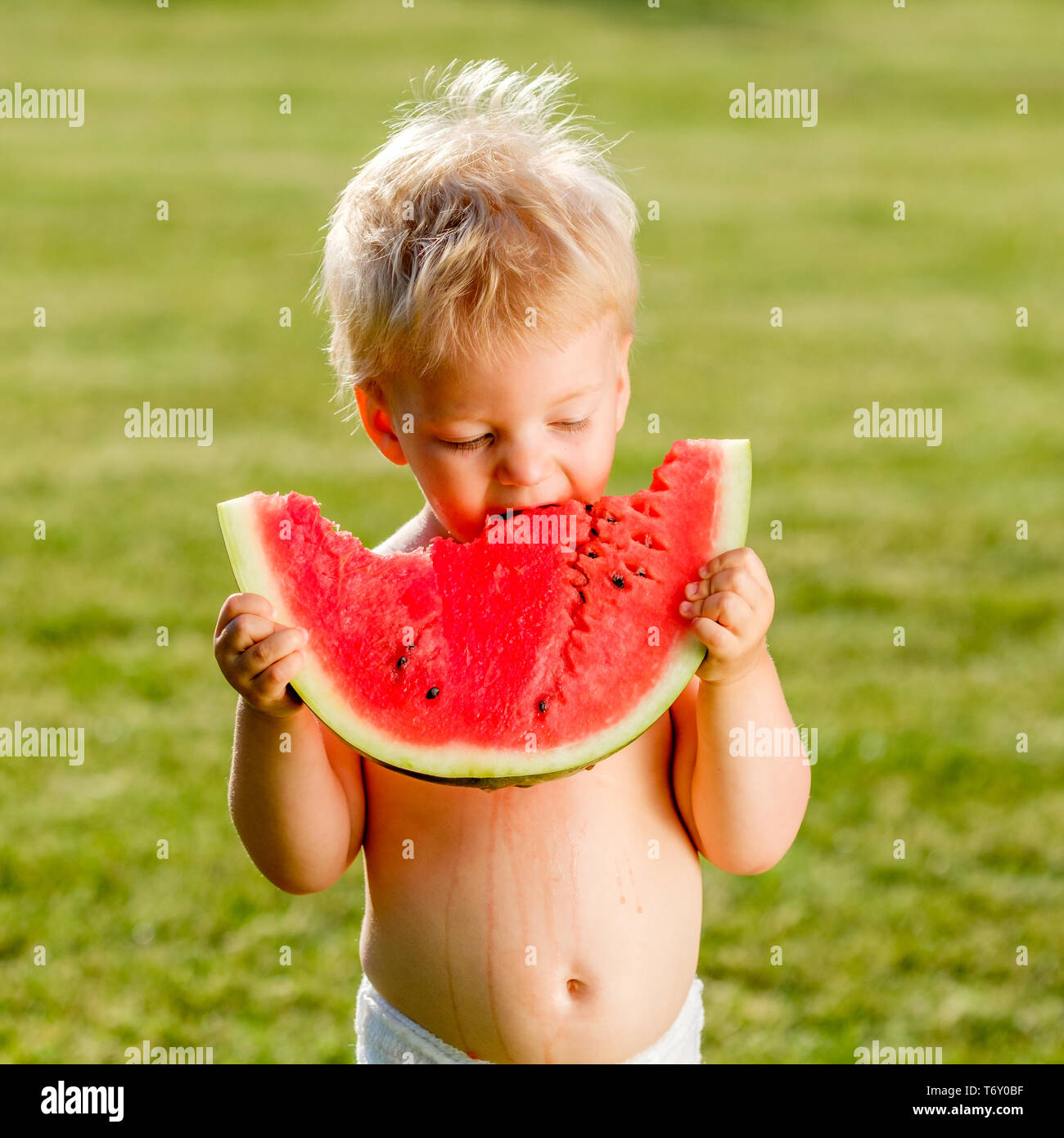 One year old baby boy eating watermelon in the garden Stock Photo