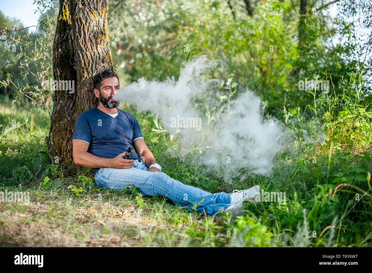 Stylish brutal man blows up a couple an vape. Electronic cigarette as alternative to tobacco