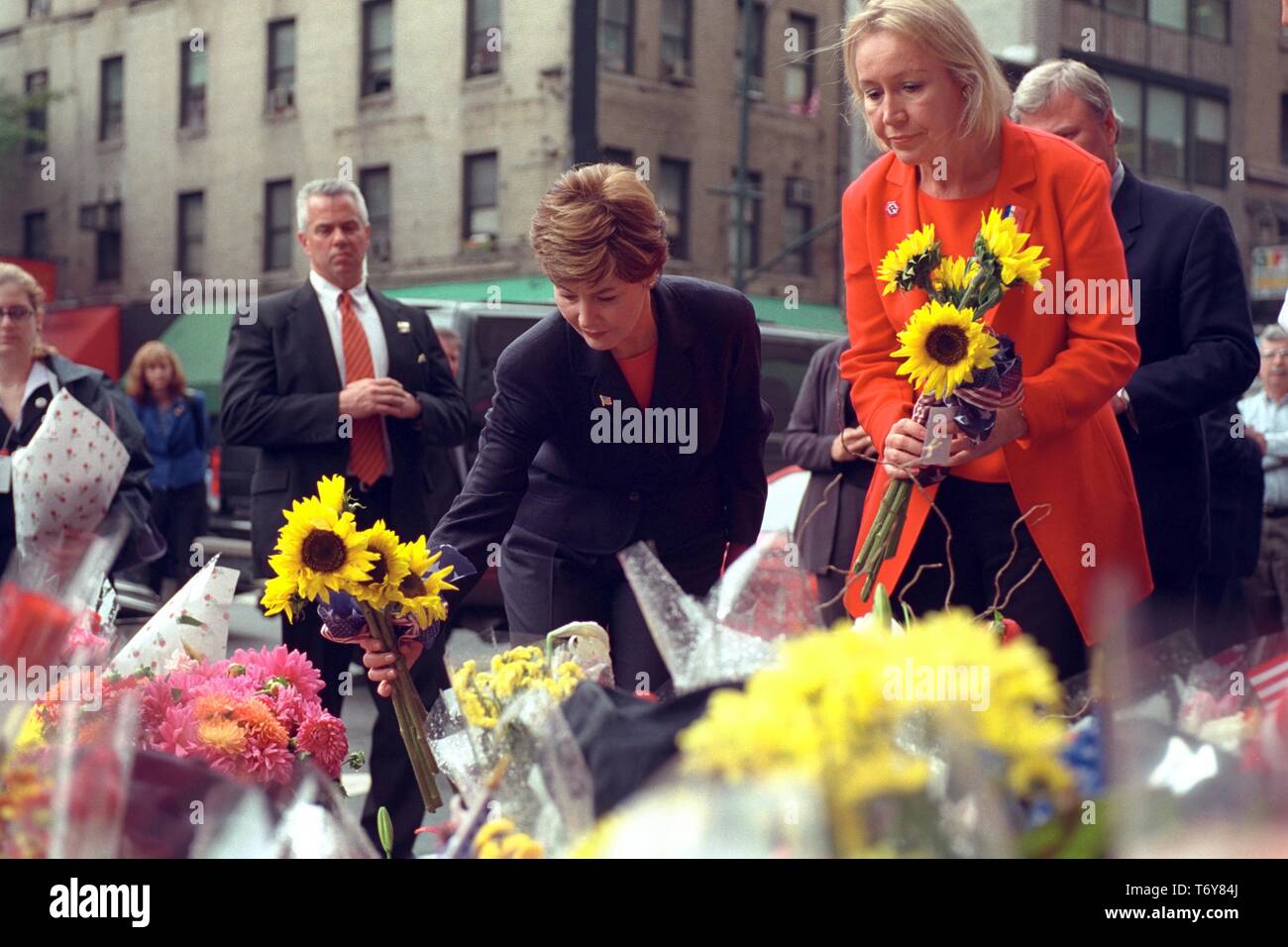 First Lady Laura W Bush and Libby Pataki, wife of New York Governor George Pataki, place sunflowers at a memorial at Battalion 9 Firehouse in New York City, honoring the firefighters who died at the World Trade Center, 2001. Courtesy National Archives. () Stock Photo