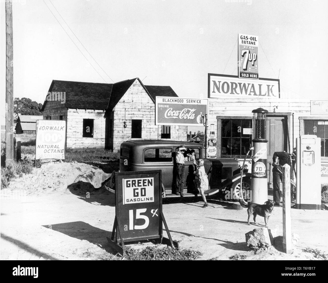 Children play on an antique car parked at a rural gas station with signs advertising drinks and gasoline, San Joaquin Valley, California, April 9, 1940. Image courtesy Dorthea Lange/US Department of Energy. () Stock Photo