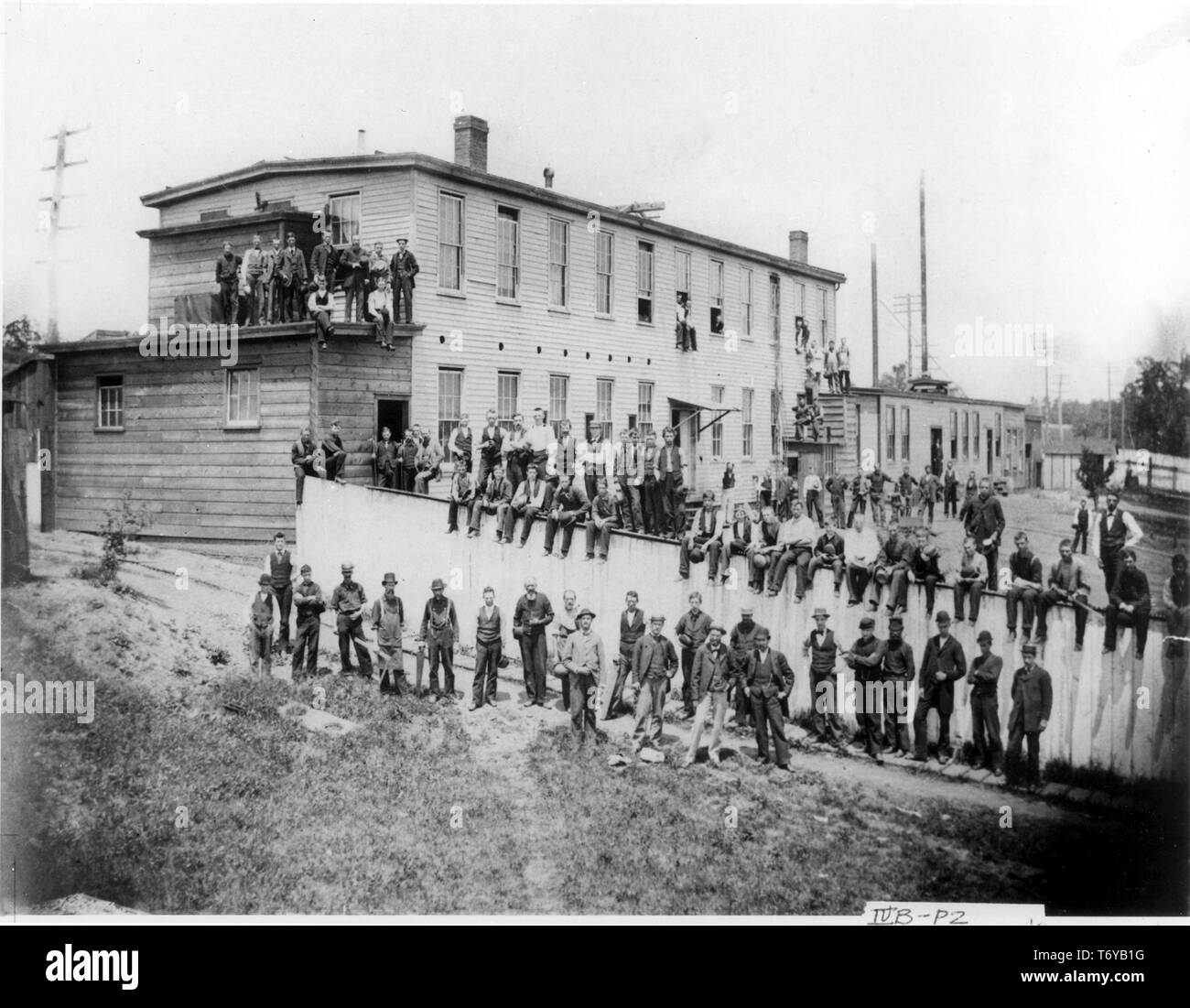 Workers sitting and standing outside Edison's first lamp factory, including  executive staff members in the front row (from left to right) Philip S  Dyer, William J Hammer, Francis R Upton, and James