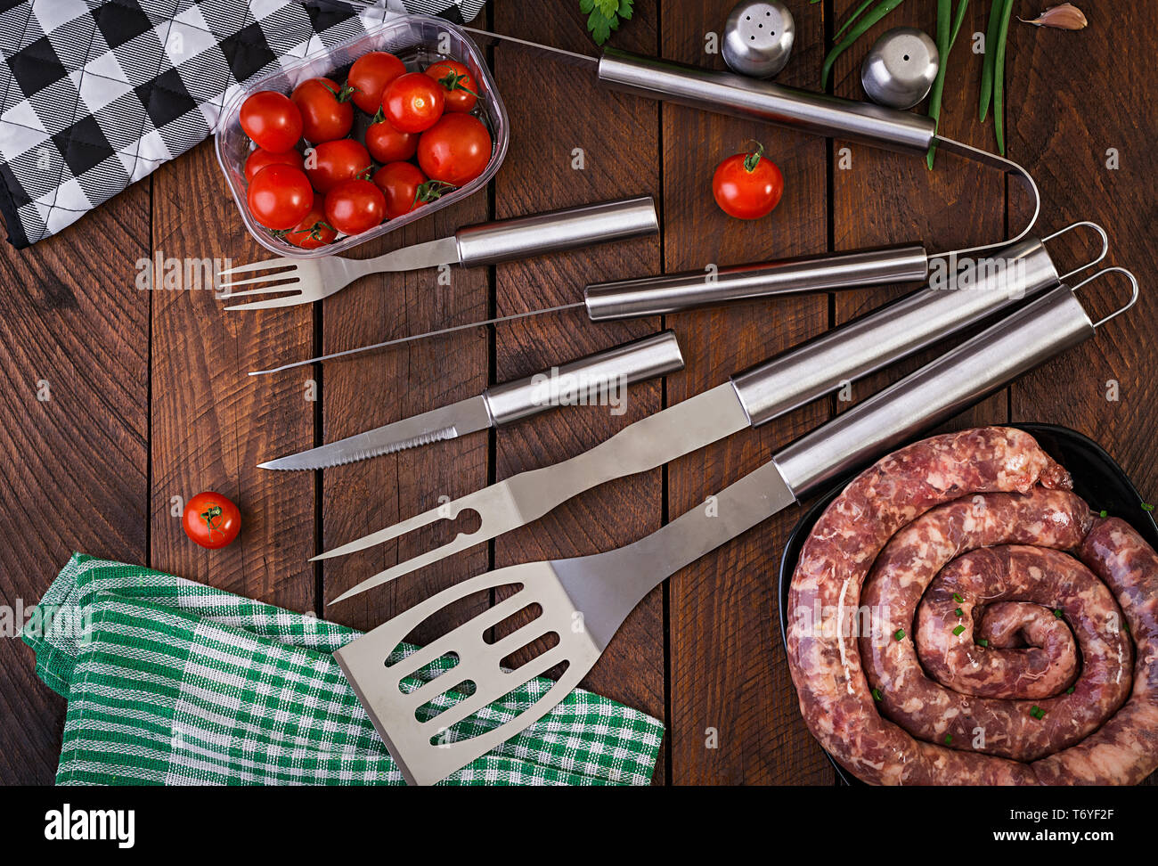 Barbecue Tools and sausage on wooden table. Flat lay, top view Stock Photo
