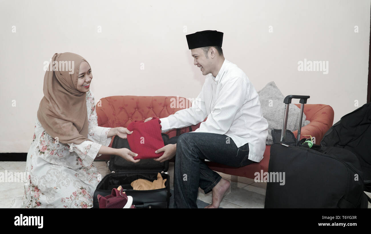 happy muslim couple man and woman put stuff in suitcase luggage prepare travelling for ramadan eid mubarak celebration -image Stock Photo