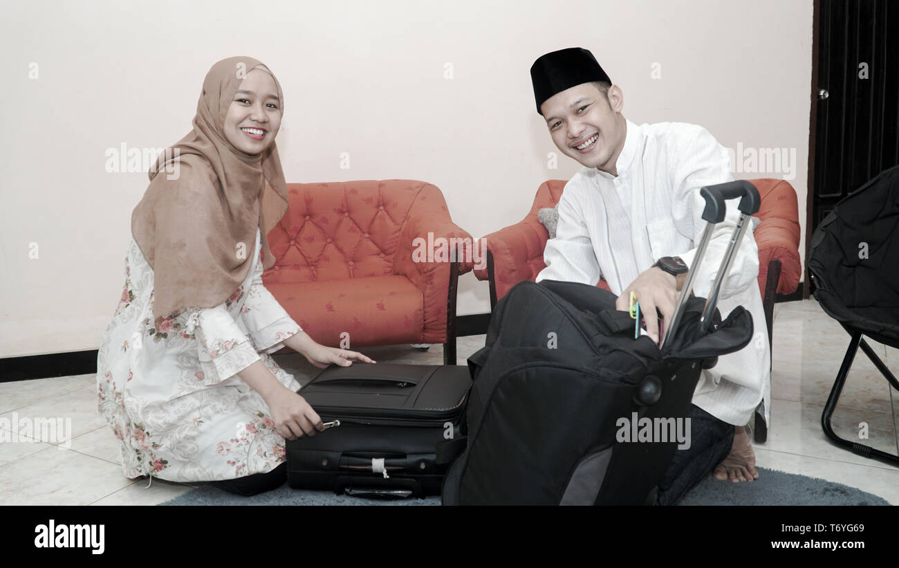 happy muslim couple man and woman put stuff in suitcase luggage prepare ...