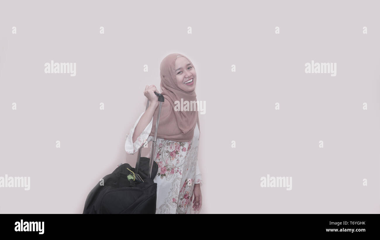 Portrait of asian muslim woman wearing head scarf or hijab holding black suitcase luggage get ready for traveling and trip Stock Photo