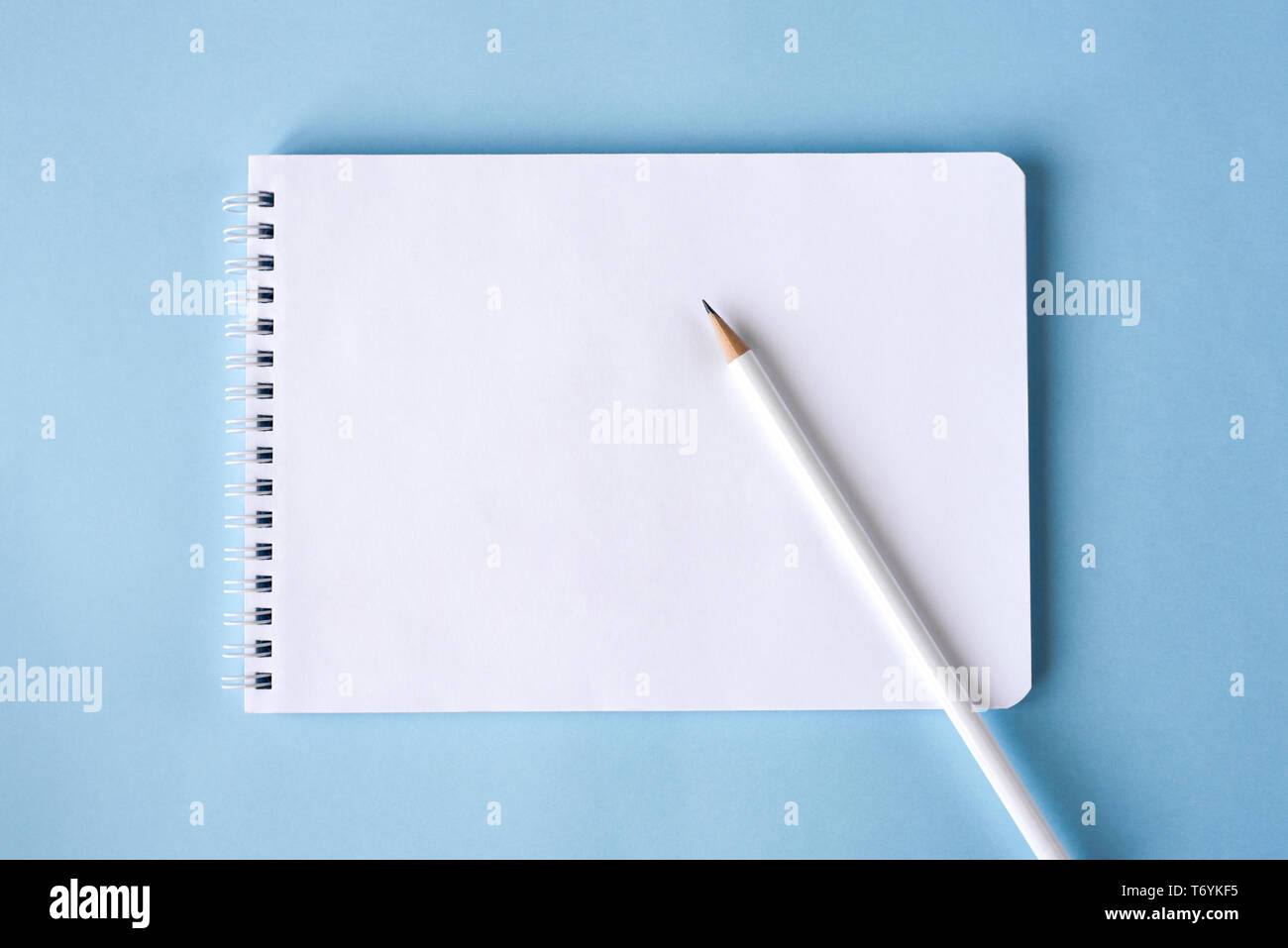 A pencil and a notebook on blue surface. Close up. Copy space for text Stock Photo